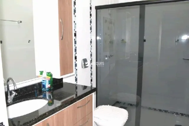 Foto de um banheiro com box de vidro e pia de granito.