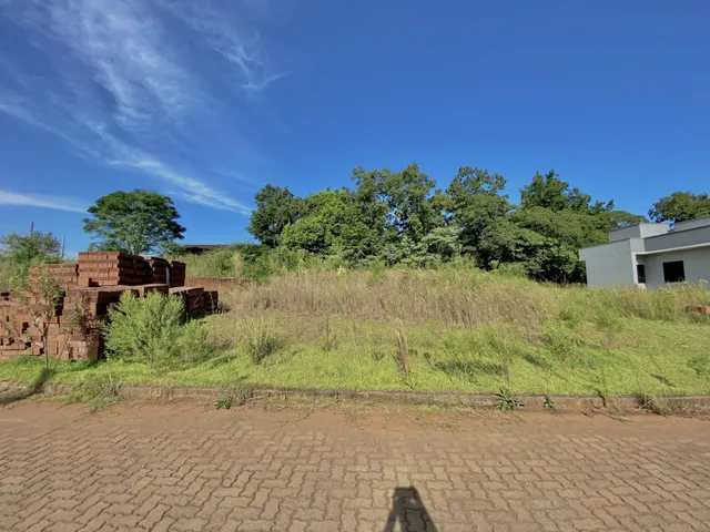 Vista externa de uma propriedade com vegetação alta e estruturas de tijolo.