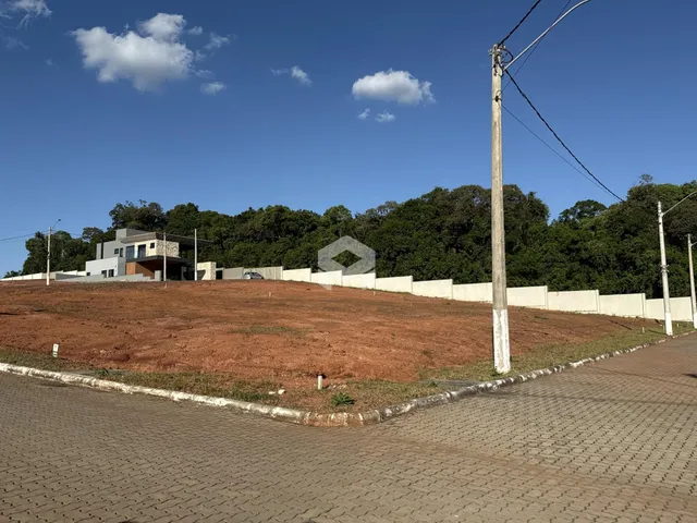 Vista externa de uma propriedade com terreno aberto e construção ao fundo.