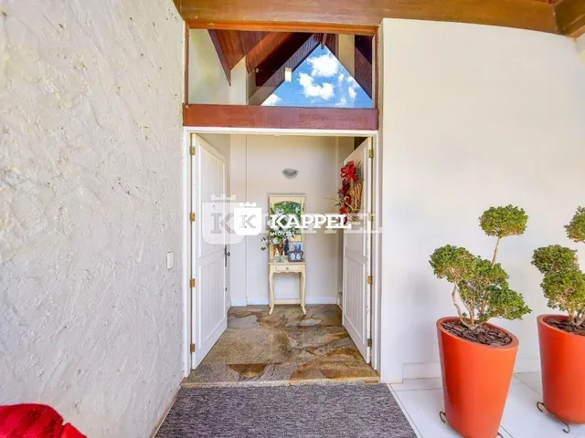 Hall de entrada com portas brancas e piso de pedra.