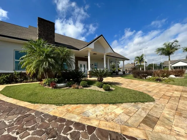 Fachada de uma casa em Lajeado, Brasil, com paisagismo frontal e calçamento de tijolos.