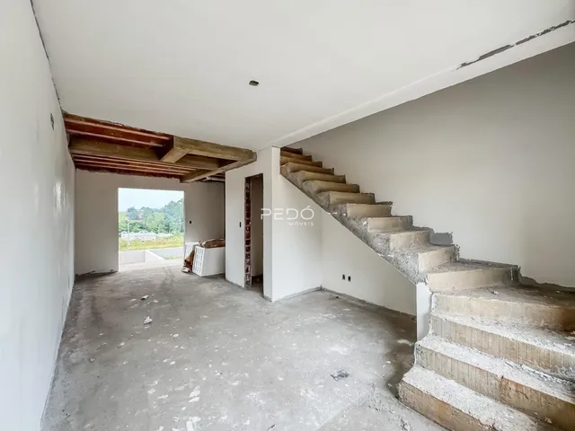 Foto de um ambiente interno com teto de madeira exposto e escadaria de concreto.