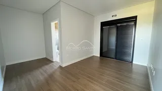 Uma sala de estar ampla com piso de madeira clara e paredes cinzas.