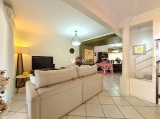 Sala de estar com sofá branco e piso de cerâmica em uma residência.