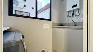 Foto de uma área da cozinha com janela e armários brancos.