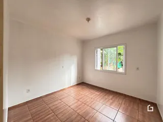 Ambiente interno com piso de cerâmica marrom e janela.