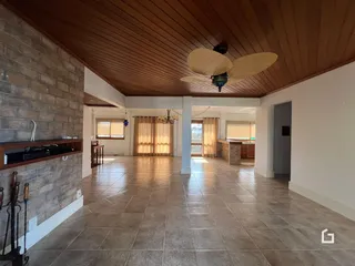 Interior de uma sala de estar com piso de cerâmica e teto de madeira.
