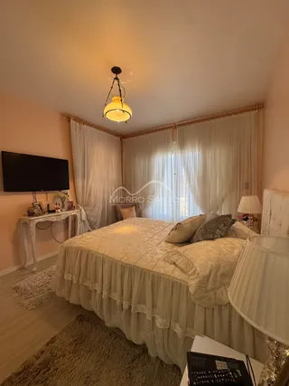 Quarto com cama grande e cortinas brancas.
