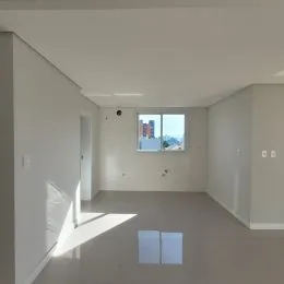 Foto interna de um ambiente com paredes brancas e piso claro.