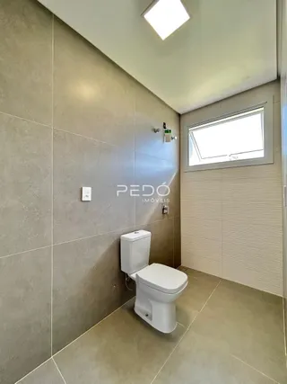 Um corredor interno com vaso sanitário branco e paredes bege.