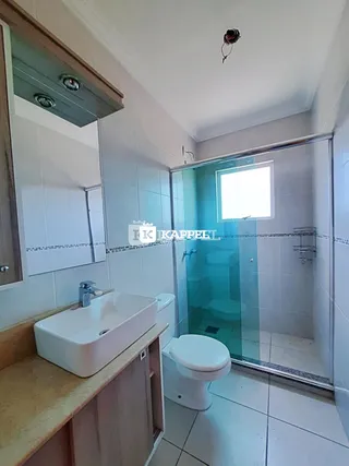 Foto de um banheiro com box de vidro e revestimento cerâmico.