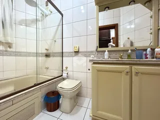 Banheiro com box de vidro e piso cerâmico.