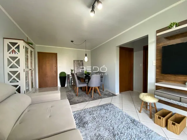 Sala de estar com sofá branco e piso claro em imóvel no Lajeado.