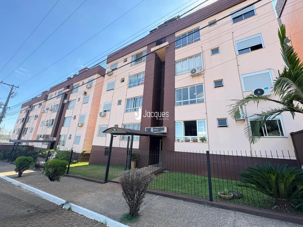 Fachada de um prédio residencial em Lajeado, Brasil, com cerca e paisagismo na frente.