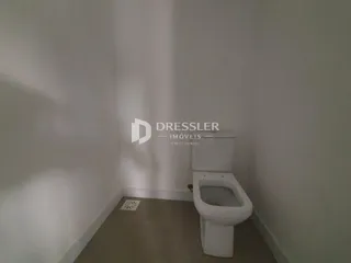 Um corredor interno com um vaso sanitário branco.
