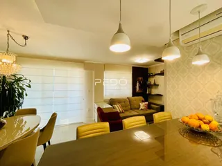 Sala de jantar com mesa de madeira e sofá de cor neutra em um imóvel no Brasil.