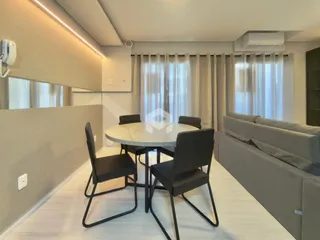 Sala de jantar com mesa redonda e cadeiras escuras em um ambiente claro.
