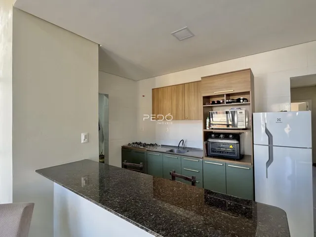 Cozinha com armários de madeira e bancada escura.