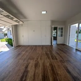 Ambiente interno com piso de madeira e armários brancos em um imóvel.