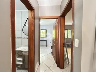 Vista de um corredor interno com portas de madeira em uma residência.