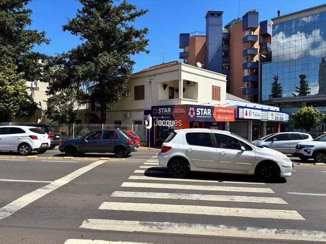 Vista da rua com veículos estacionados em frente a um edifício residencial.