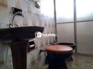 Foto de um banheiro mostrando a pia e o vaso sanitário com revestimento de azulejos.