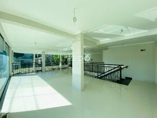 Ambiente interno de uma sala ampla com piso de cerâmica e sacada.