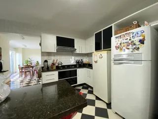 Vista da cozinha com armários brancos e piso xadrez preto e branco.