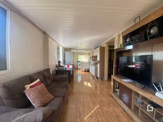 Sala de estar com sofá e piso de madeira em uma residência.