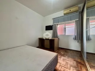 Foto de um quarto com cama e piso de madeira em uma residência.