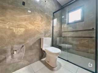 Foto interna de um banheiro com revestimento de parede em tons de bege e marrom.