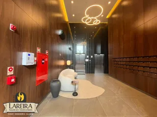 Corredor moderno com paredes de madeira e piso claro em um imóvel.