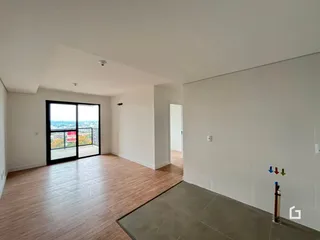 Sala de estar com piso de madeira e porta de vidro abrindo para a vista.