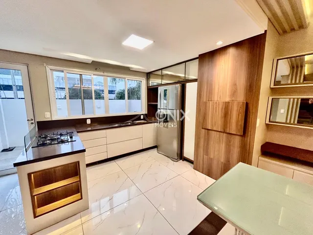 Vista de uma cozinha moderna com armários brancos e piso de mármore claro.