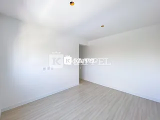 Foto de um corredor interno com piso de madeira clara e paredes brancas.