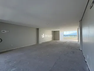 Vista interna de um espaço vazio com paredes brancas e piso de concreto.