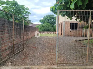 Vista da propriedade com cerca de tela e muro de tijolos.