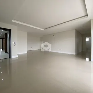Vista de um corredor amplo com paredes brancas e piso claro.