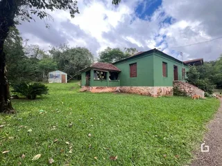 Fachada de uma casa verde com fundação de pedra em Lajeado.