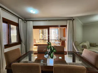 Sala de jantar com mesa de vidro e vista para a área externa.