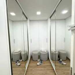 Uma passagem com espelhos e piso de madeira clara.