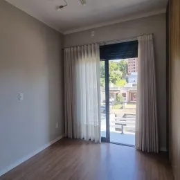 Ambiente interno com piso de madeira e cortinas claras.