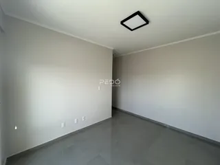 Imagem de um ambiente interno com paredes brancas e piso cinza.