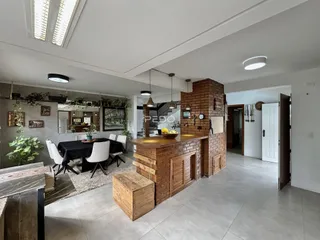 Ambiente de sala de jantar e cozinha com parede de tijolos aparentes em imóvel em Lajeado.
