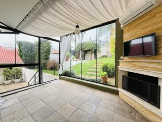 Vista de uma área comum com acesso a um jardim através de grandes portas de vidro.