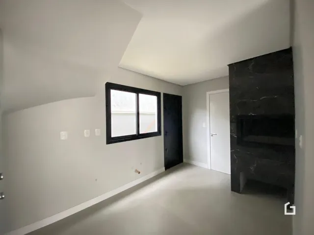 Interior de uma sala com paredes brancas e uma grande janela.