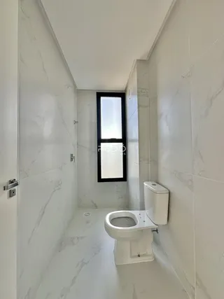 Um corredor de banheiro com revestimento de mármore branco e um vaso sanitário.