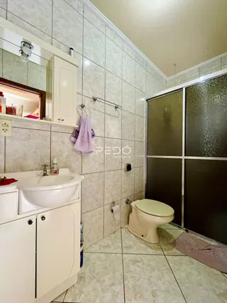 Banheiro com revestimento cerâmico nas paredes e piso claro.