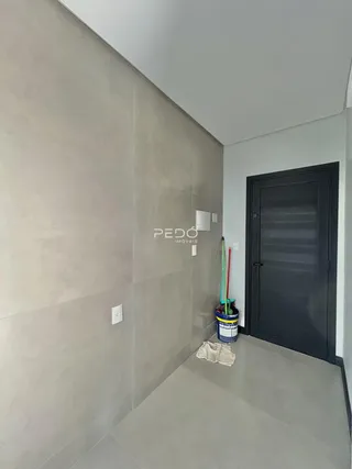 Vista de um corredor interno com paredes cinzas e piso claro.