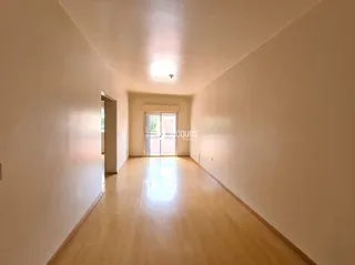 Corredor interno de uma residência com piso de madeira clara.